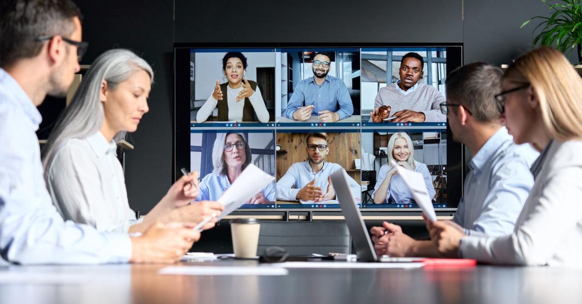 A hybrid meeting space: colleagues around the table and remote participants on the screen